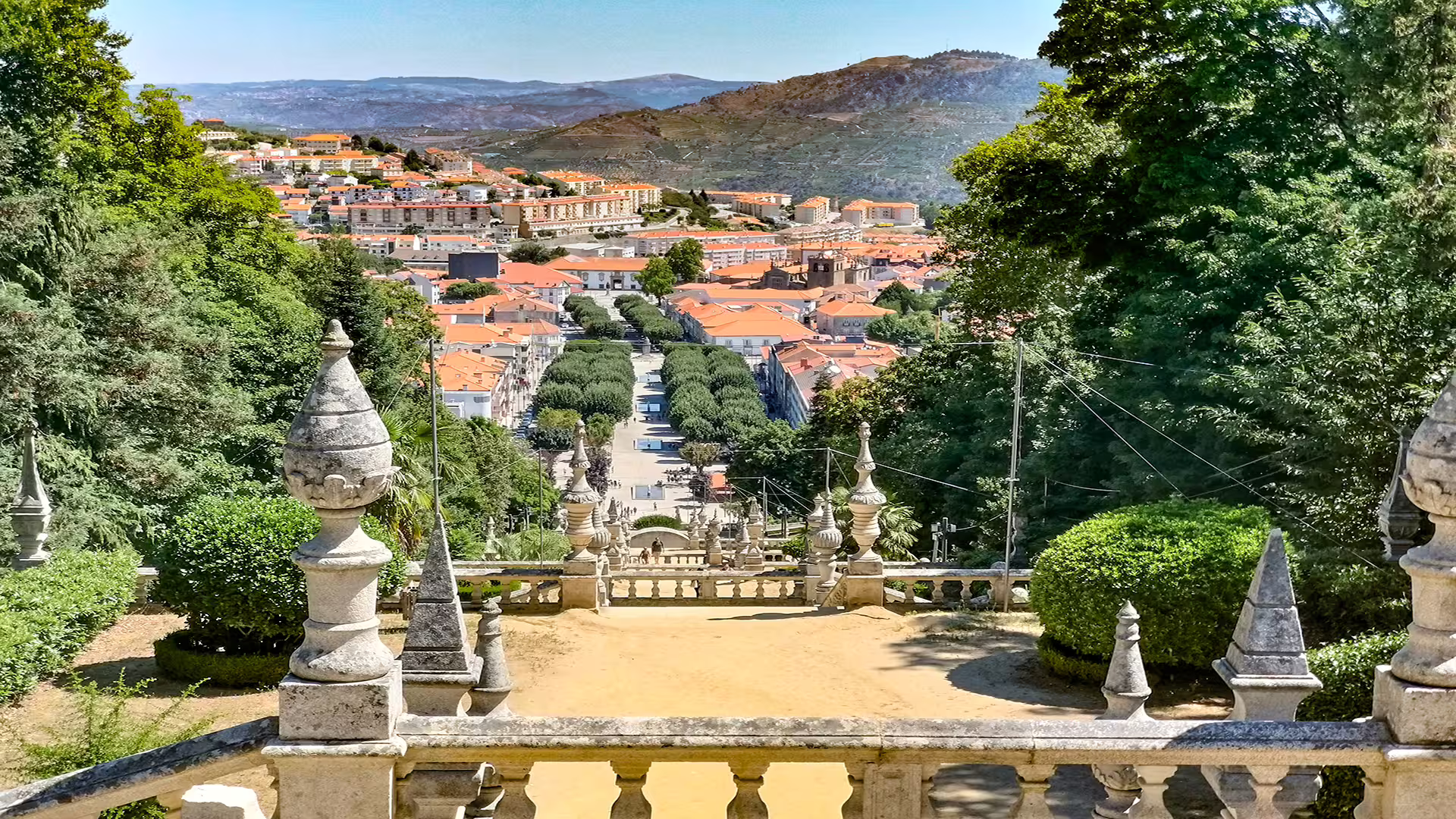 Scenic view of Lamego from a historic staircase, showcasing vibrant rooftops and lush greenery in the Dão wine region.