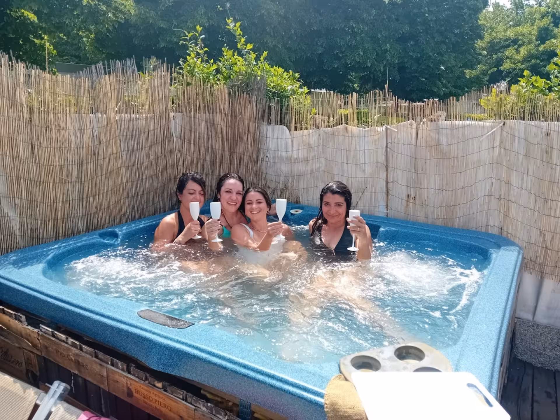 Group of friends enjoying a refreshing soak in the Langhe Spa hot tub, toasting with drinks amidst a serene setting.