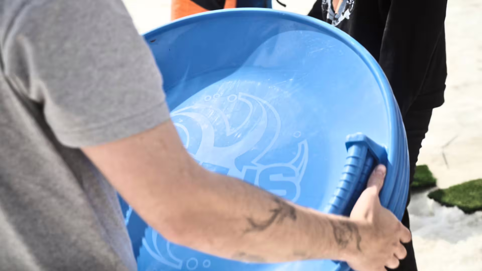 Guests hold a blue sled for snow play on Langjökull Glacier during Red Glacier monster truck tour from Gullfoss