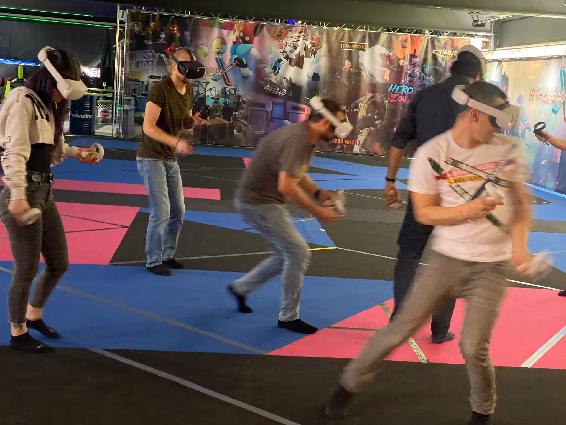 Friends playing Laser Game VR 25 in a neon arena, wearing VR headsets and controllers in team battle