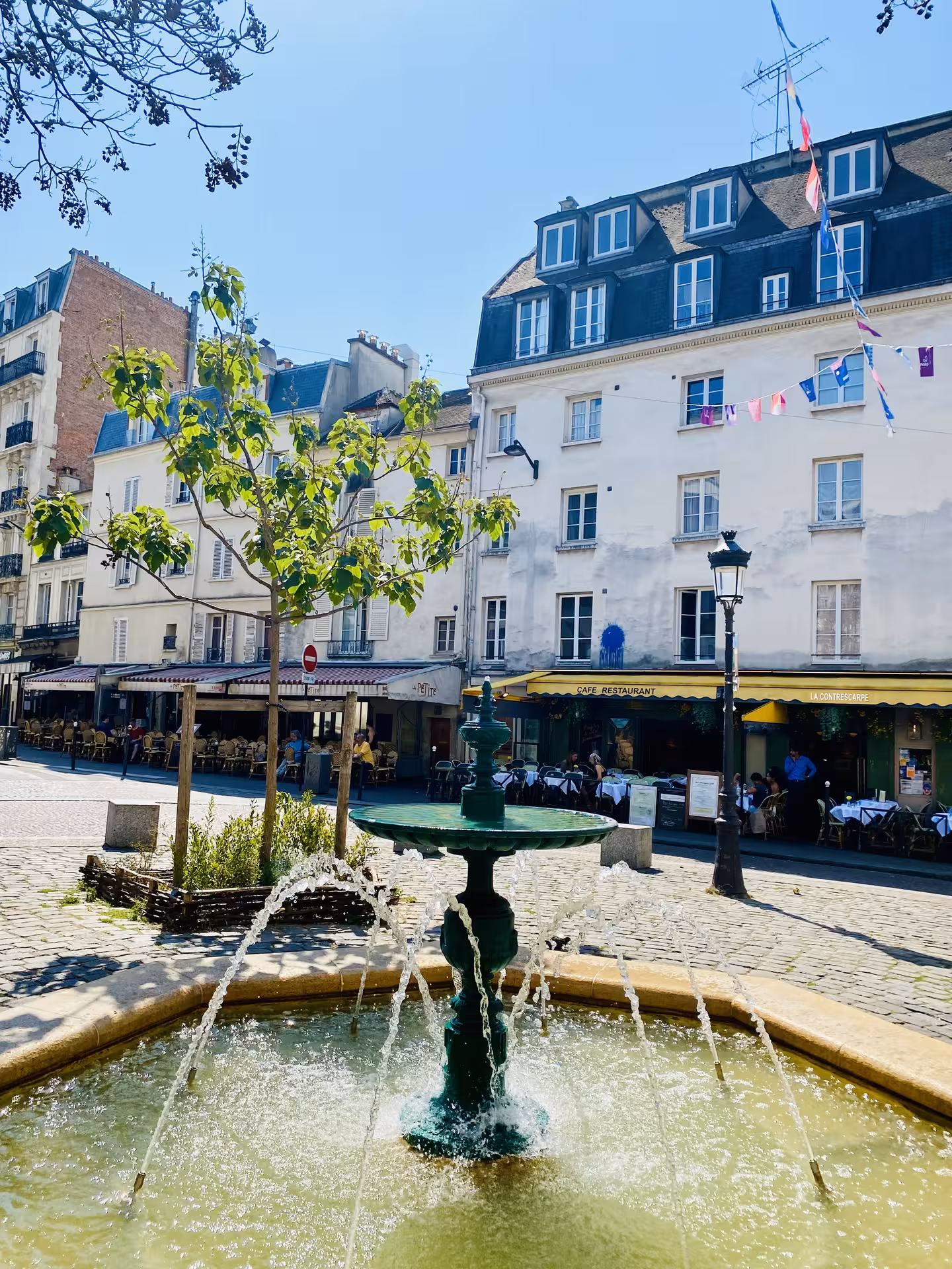 Discover hidden gems in the Latin Quarter, featuring a quaint fountain and lively cafes under the Parisian sun.