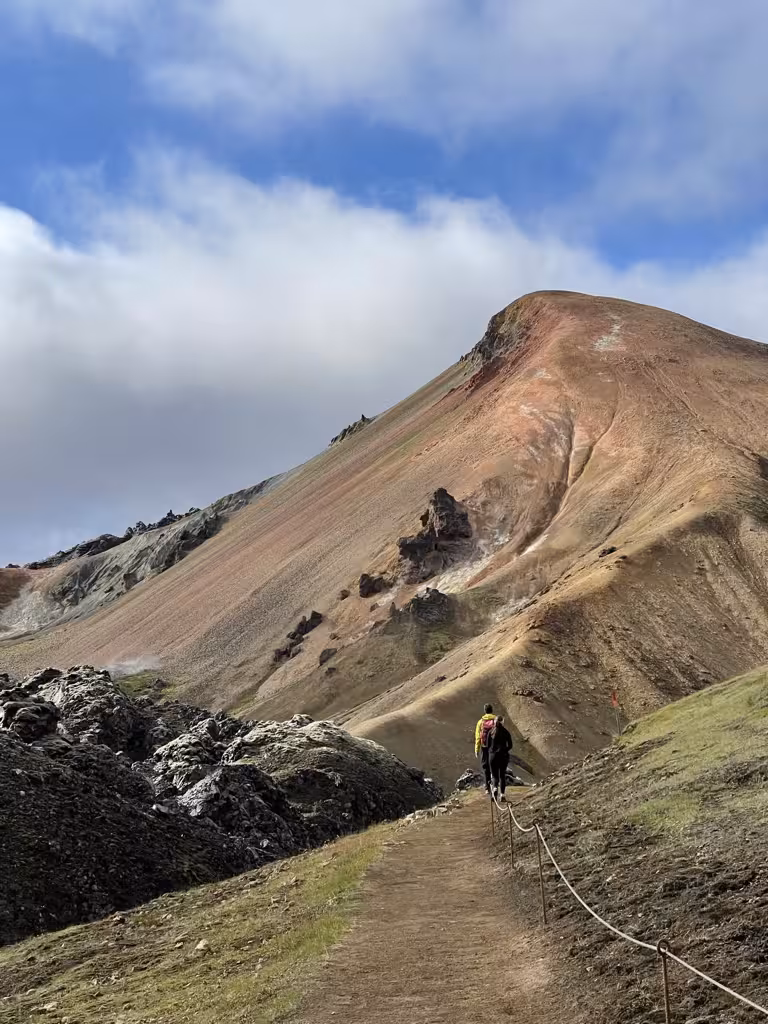Solo hiker ascends a colorful volcanic mountain on the challenging Laugavegur Trail, showcasing Iceland's unique terrain.