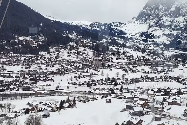 Scenic winter view of a snow-covered Swiss village nestled in the Lauterbrunnen Valley with surrounding Alps.