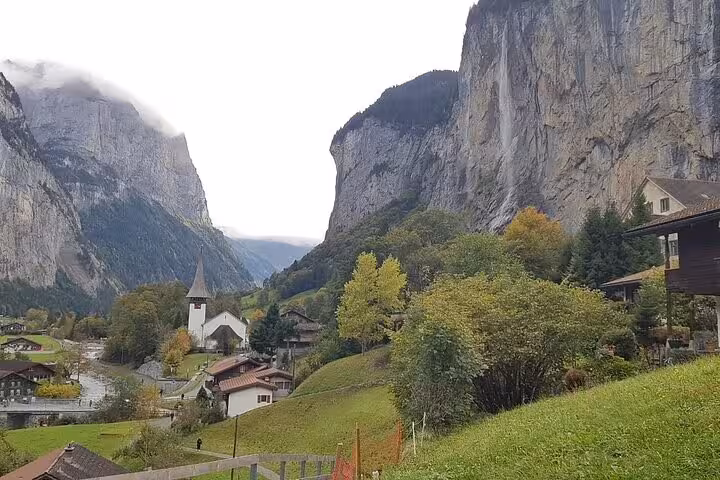 Picturesque Lauterbrunnen valley with towering cliffs and a quaint church, showcasing the natural beauty of the Swiss Alps.