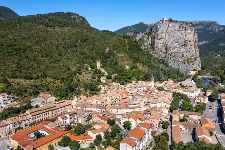 Picturesque village with terracotta rooftops surrounded by lush greenery and dramatic cliffs.