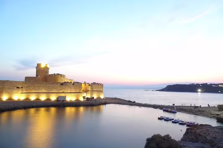 Sunset view of Le Castella fortress reflected in calm Ionian Sea waters near Isola Capo Rizzuto on private walking tour