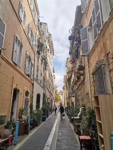 Narrow cobblestone lane with shutters and plants in Le Panier, Marseille, on the oldest neighborhood walking tour