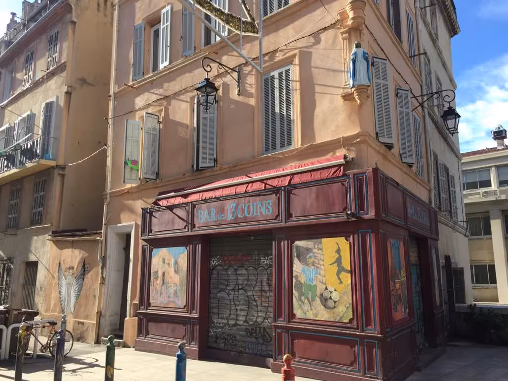 Corner café facade in Le Panier Marseille, pastel shutters and street art on the Oldest District walking tour
