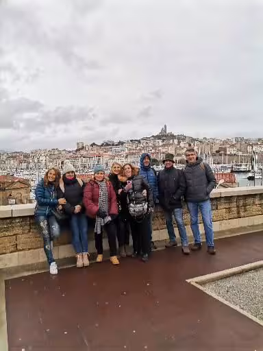 Small group posing at Marseille Vieux-Port viewpoint with city skyline during Le Panier walking tour
