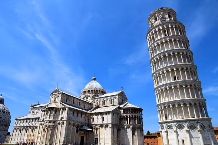 Stunning view of the Leaning Tower of Pisa and Pisa Cathedral under a clear blue sky, highlighting Italy's architectural marvels.