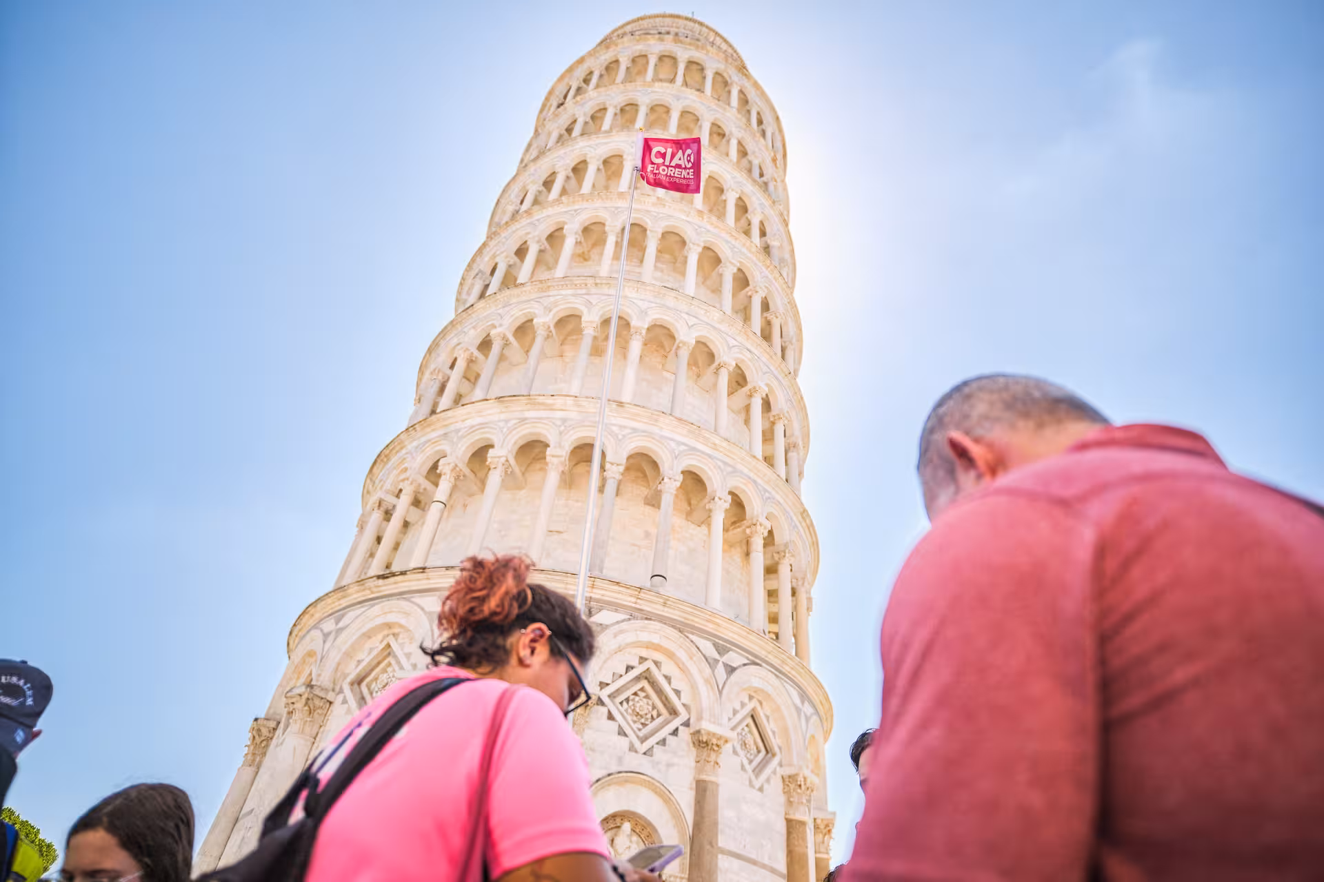 Close-up view of tourists at the base of the Leaning Tower of Pisa during the Florence half-day tour.