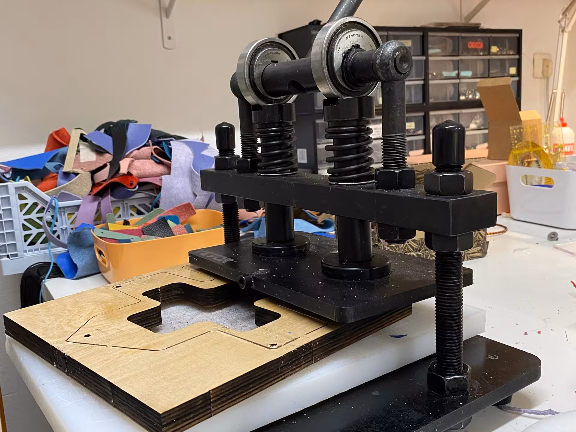 Leather cutting machine used in Verona's wallet-making workshop surrounded by colorful material scraps.