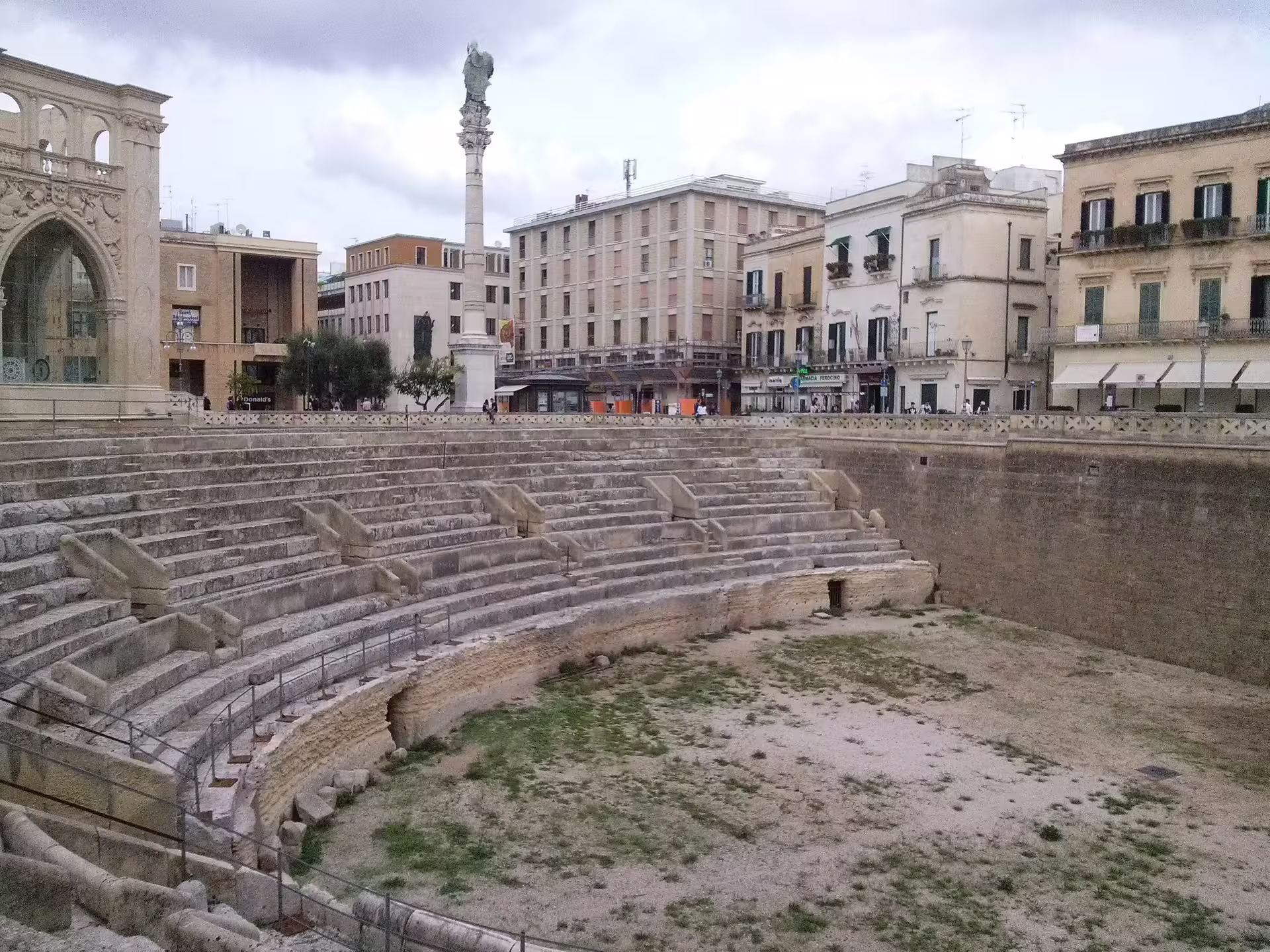 Roman amphitheatre ruins in central Lecce surrounded by historic palazzi on Enchanting Puglia driving itinerary