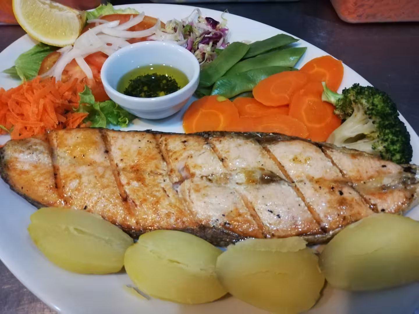 Leeward Islands grilled salmon fillet with boiled potatoes, carrots, salad and herbs served on a Caribbean culinary tour