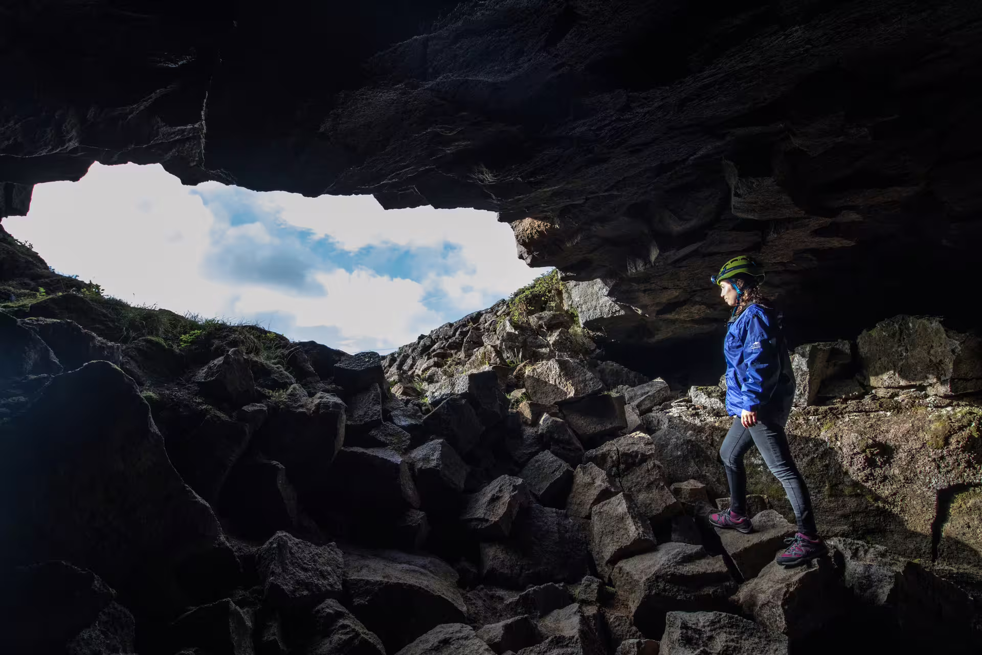 Adventurer explores the rugged terrain of Leidarendi Lava Tunnel, highlighting Iceland's unique small group caving experience.