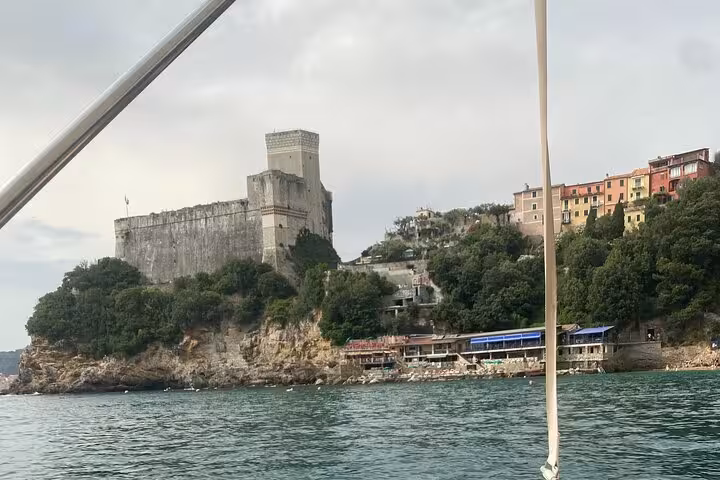 View from a boat of the historic castle and colorful cliffs of Lerici on the La Spezia coastal tour.