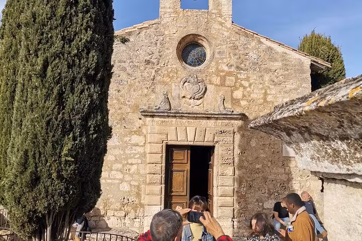 Historic stone chapel in Les Baux-de-Provence with visitors, a cultural stop on the Saint Rémy tour