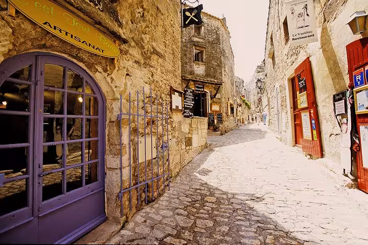 Quaint cobblestone street in Les Baux de Provence, lined with artisan shops and historic buildings.