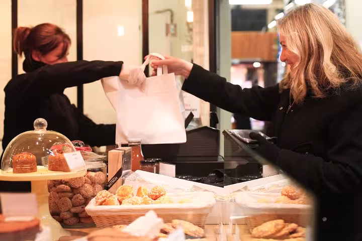 Customer purchasing pastries at Les Halles Paul Bocuse during a morning food market tour, showcasing local delicacies.
