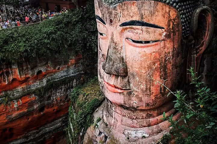 Close-up of the Leshan Giant Buddha surrounded by lush greenery, a highlight of Chengdu to Leshan two-day tour.