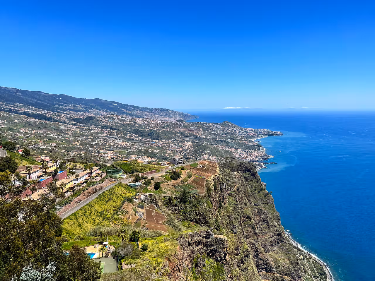 Breathtaking view of Madeira's coastline from Cabo Girão, showcasing lush greenery and the Atlantic Ocean.
