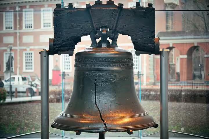 Liberty Bell with visible crack on display in Philadelphia with Independence Hall in background