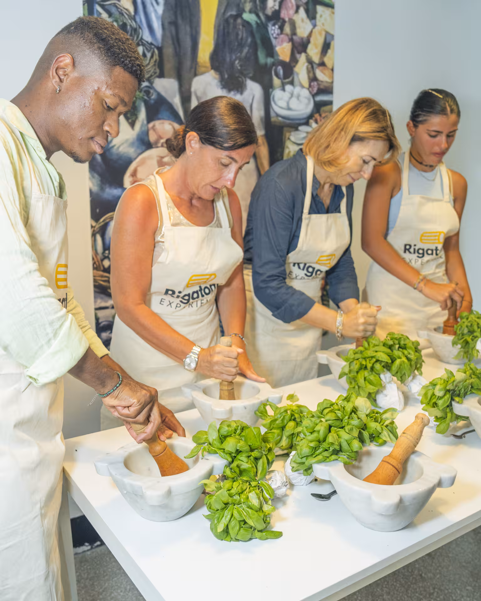 Participants learning to make pesto with fresh basil in a Ligurian cooking class.