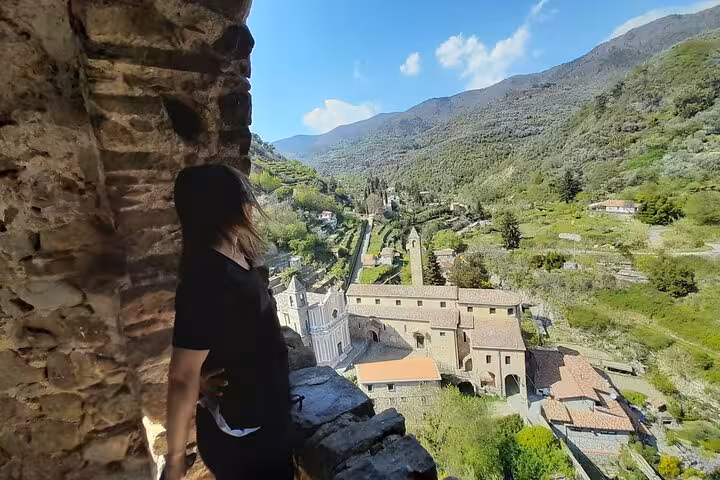 Traveler enjoys a panoramic view of historic Ligurian village from a stone archway.