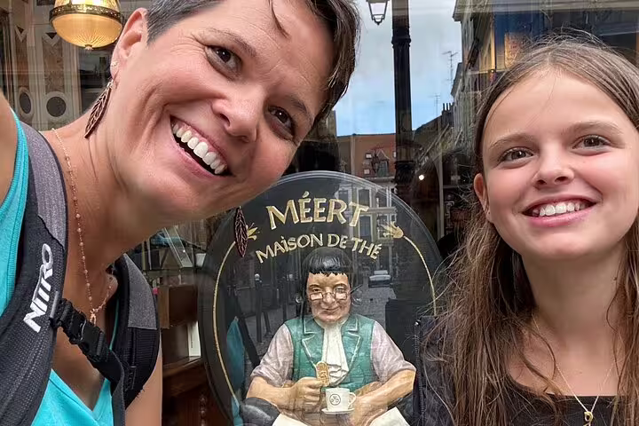 Smiling duo at Meert Maison de Thé window in Lille, discovering Old Town sights on a scavenger hunt tour