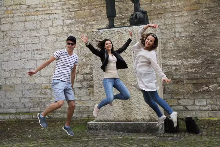 Group jumping by historic stone wall on Lille scavenger hunt, fun city highlights walking tour moment