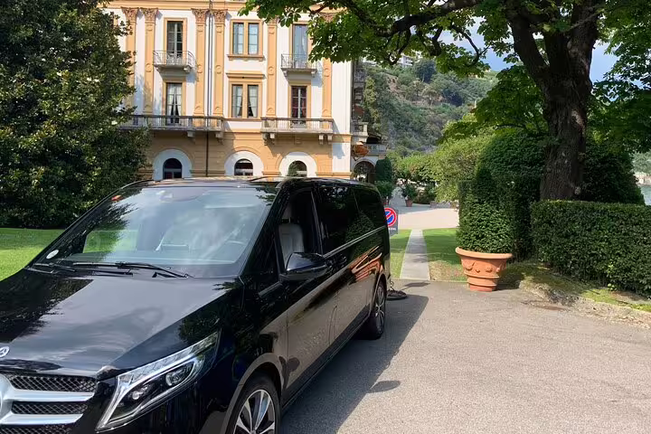 Luxurious private transfer vehicle parked outside a historic Milanese villa, offering premium airport transport.