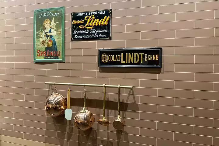 Vintage Lindt and Sprüngli signs with copper chocolate-making tools on display at Lindt Factory.