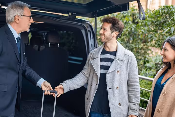 Friendly driver assisting smiling passengers with luggage for a seamless Lisboa to Porto transfer experience.