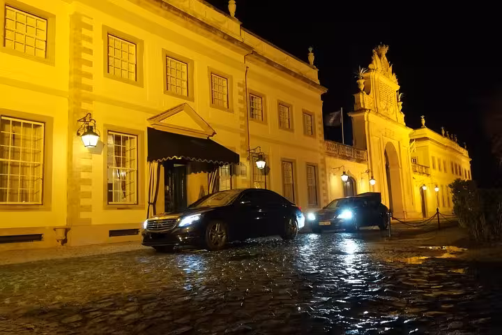 Night pickup for Lisbon airport shuttle transfer with private car outside a Lisbon hotel on wet cobblestones