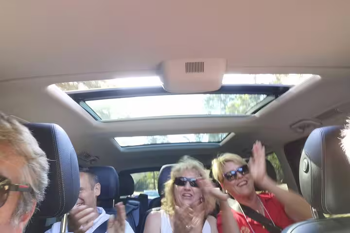 Passengers enjoying a joyful ride in a Lisbon airport shuttle with a panoramic sunroof, offering comfort and scenic views.