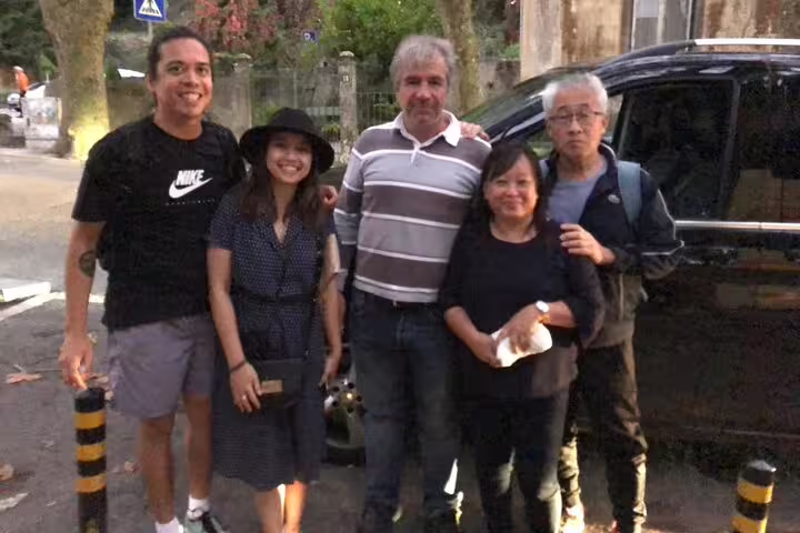 Group of travelers smiling in front of a Lisbon airport shuttle, ready for a convenient and comfortable transfer service.