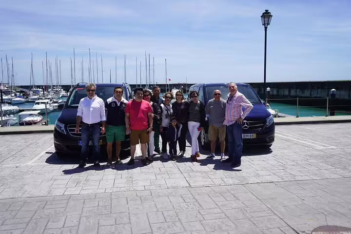 Group enjoying Lisbon airport shuttle service with comfortable vans, scenic marina backdrop, and convenient travel options.