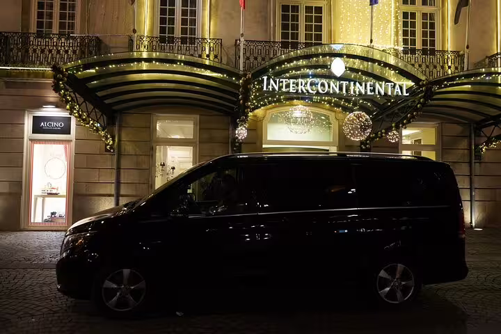 Luxurious Lisbon airport shuttle van parked outside the illuminated Intercontinental hotel, offering premium city transfers.