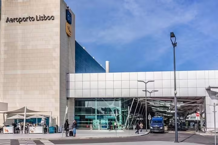 Lisbon Airport transfer service with modern vehicles for convenient travel, featuring the main terminal entrance under a clear sky.