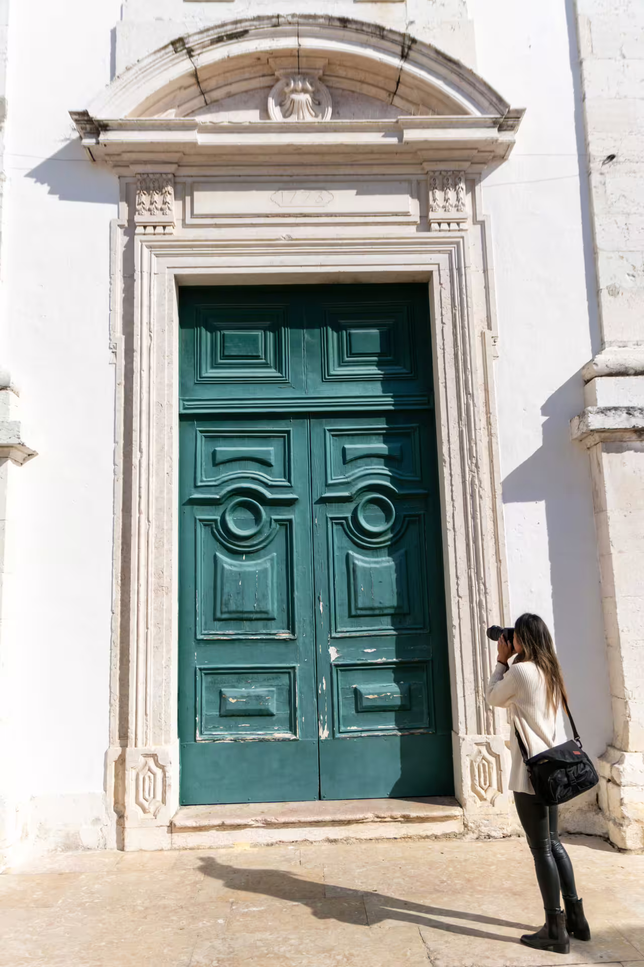 Photographer capturing the intricate details of a historic green door in Lisbon's Alfama district during a guided photo walk.