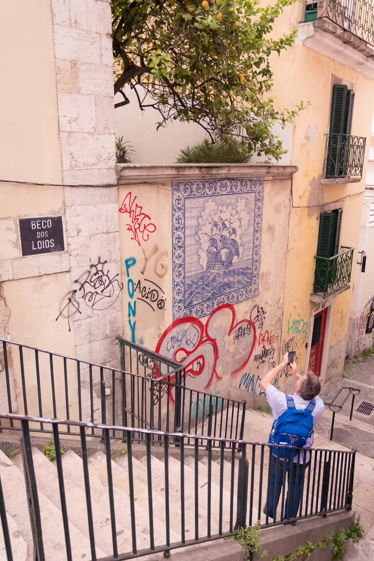 A tourist photographs vibrant street art and historic tiles in the charming Alfama district during a Lisbon photo walk.