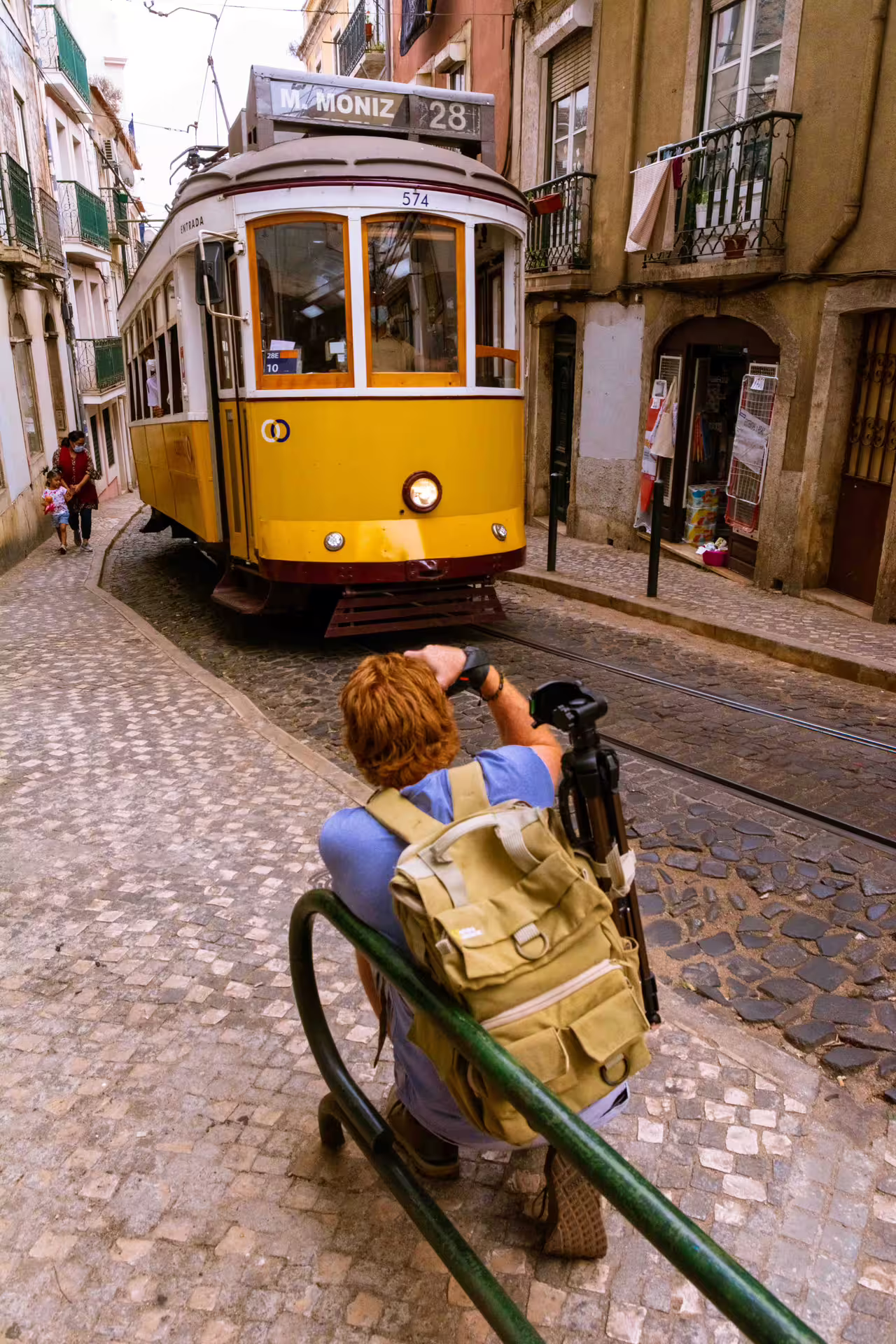 Photographer capturing iconic yellow tram on cobblestone street during Alfama Photo Walk in Lisbon, led by a local guide.