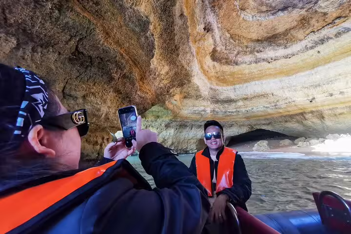 Tourists enjoy a boat ride exploring Algarve's stunning Benagil Cave on a private 2-day tour from Lisbon, capturing memorable moments.