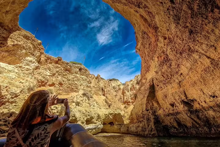 A tourist captures the stunning rock formations of Algarve's Benagil Cave from a boat during a private two-day tour from Lisbon.