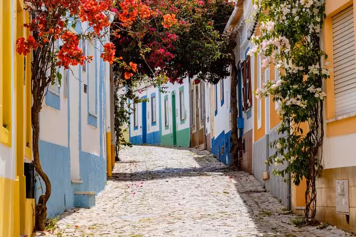 Charming cobblestone street with colorful houses in Algarve, a highlight of the Lisbon to Algarve transfer tour.