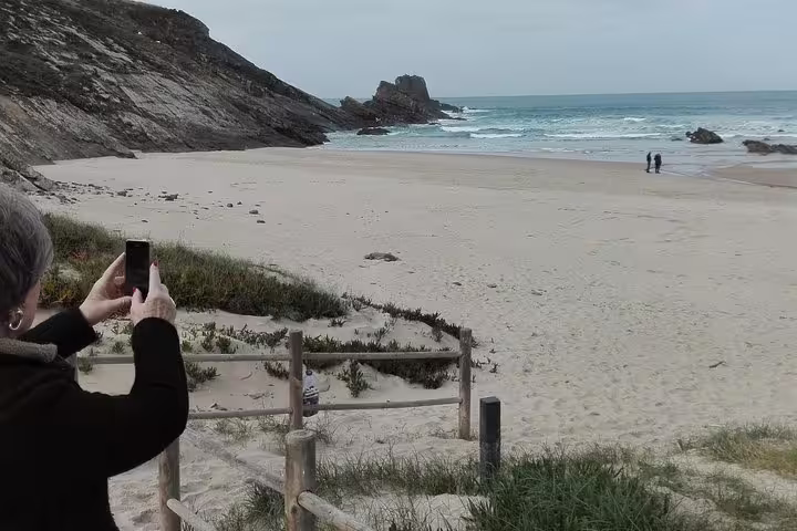 Scenic coastal view on the Lisbon to Algarve tour, featuring a tranquil beach, rugged cliffs, and ocean waves, perfect for photography.