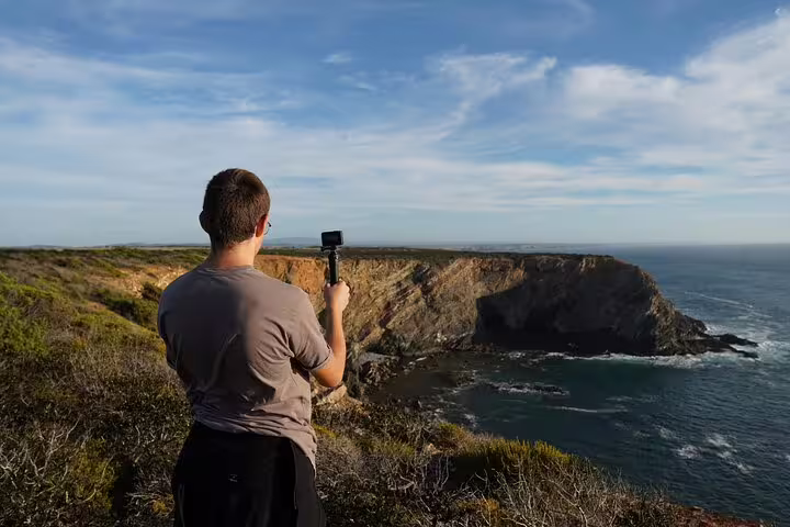 Traveler capturing stunning coastal views on a Lisbon to Algarve tour, featuring scenic cliffs and ocean vistas.