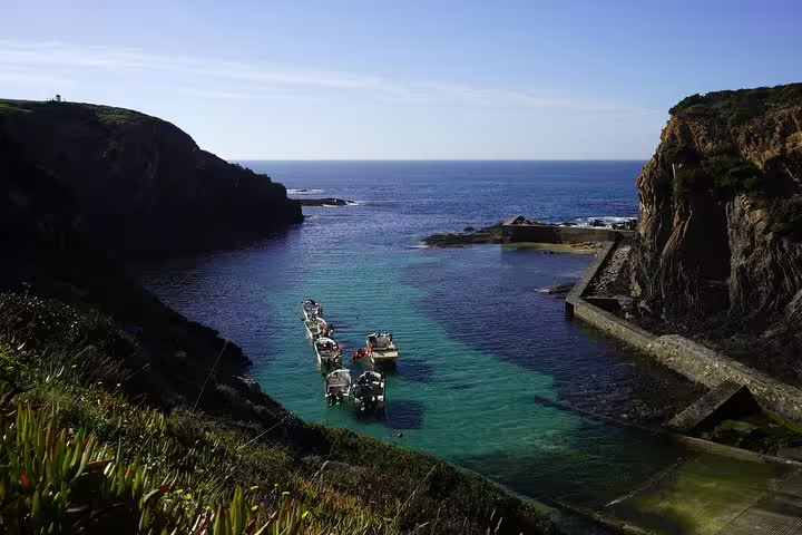 Scenic coastal view of small boats in a serene turquoise bay, perfect for Lisbon to Algarve tours with stunning ocean stops.