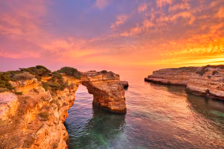Experience a breathtaking sunset over Algarve's sea cliffs on a Lisbon to Algarve private Mercedes transfer.