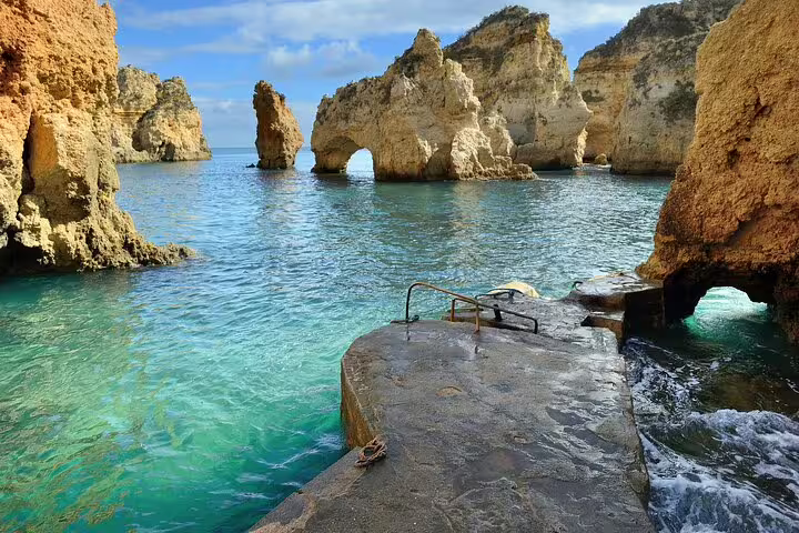 Idyllic Algarve coast with stunning rock formations and crystal-clear waters, perfect for a scenic Lisbon to Algarve private transfer.
